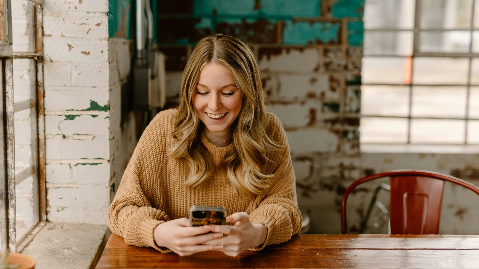 Vrouw bekijkt haar geldzaken op haar telefoon aan tafel